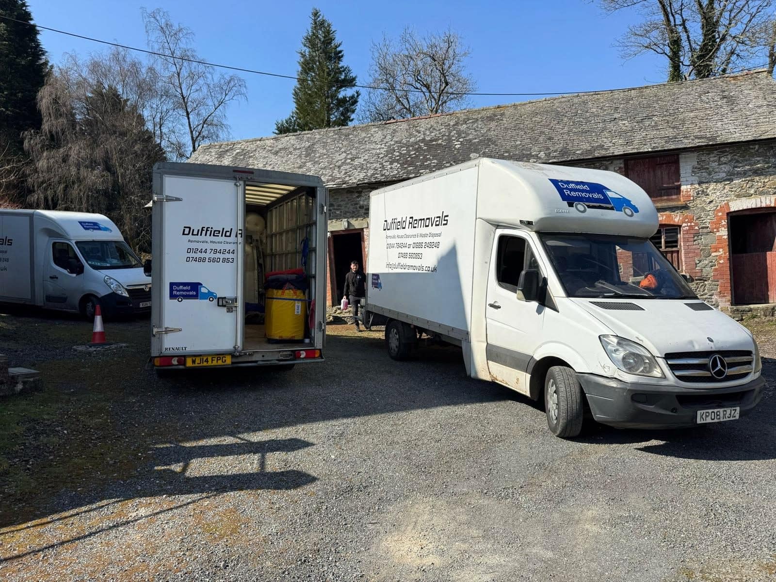 Three Duffield Removals vans at a rural stone barn, one open and loaded